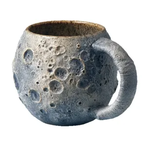 Moon surface ceramic coffee mug with unique crater texture, artistic handcrafted planetary drinkware design.