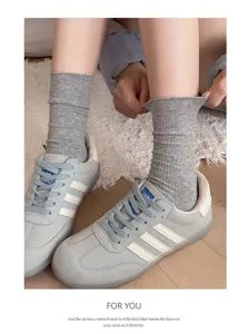 Nahaufnahme grauer gerippter Mittelsocken mit Freizeitschuhen, weiche Strickstruktur.