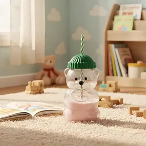 Cute bear glass straw cup with green beanie lid and striped straw in cozy room setting.