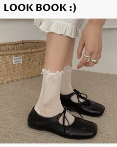 Vue détaillée de chaussettes mi-mollet en dentelle blanche avec nœud et chaussures noires.