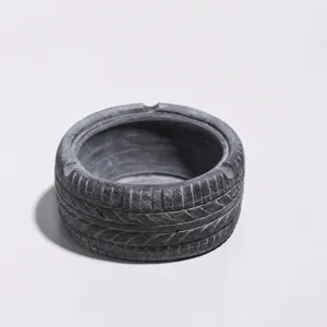 Gros plan détaillé d'un cendrier créatif rétro en forme de pneu gris foncé, compact et durable.
