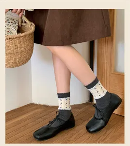 Nahaufnahme von süßen koreanischen Blumen-Spitzensocken kombiniert mit schwarzen flachen Schuhen.