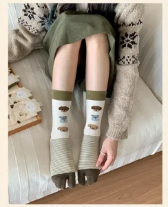 Detail shot of cute cream split toe socks with cartoon puppy patterns and cozy striped design.