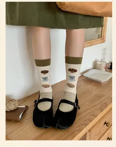 Detail view of cream split-toe mid-calf socks featuring cute cartoon puppy patterns and stripes.