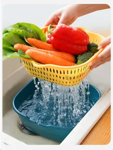 Detailed view of a double-layer draining basket in action, washing fresh vegetables easily.