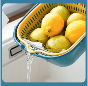 Close up view of dual layer plastic drainage basket washing fresh lemons and pears in kitchen sink.