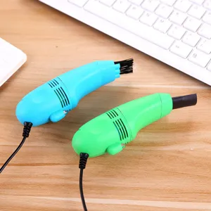 Detailed close-up of mini USB desktop vacuum cleaner with brush on wooden office desk.