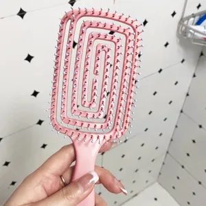Pink spiral vent hair comb close-up, hollow curved massage brush for fluffy hair styling.