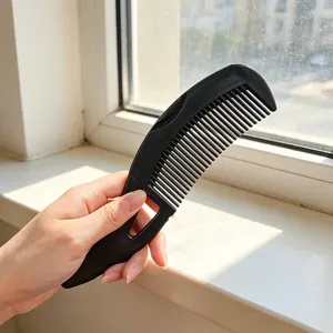 Black plastic hair comb with hollow handle for daily scalp massage and hair care use.