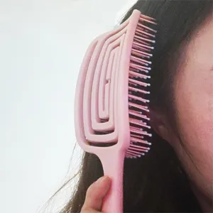 Close-up detail view of the pink curved vent hairbrush in use, showing flexible design.