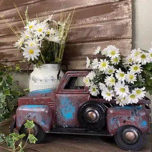 Vintage metal pickup truck model with white daisy flowers for rustic home and holiday decor.