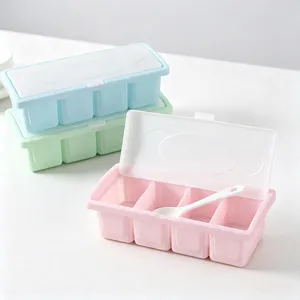 Multifunctional 4-grid plastic seasoning box with spoon and lid for kitchen storage.