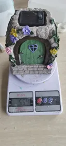 Detailed view of the solar fairy garden house ornament being weighed on scale, showing size.