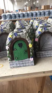 Resin fairy garden door with solar light detail, showing textured stone arch and green door.