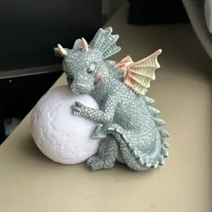 Detailed close-up of a cute sleeping baby dragon resin sculpture hugging a glowing moon.