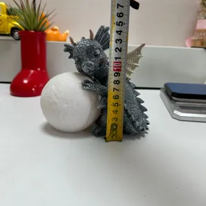 Close-up detail showing resin dragon figurine with glowing moon and measuring tape for size check.