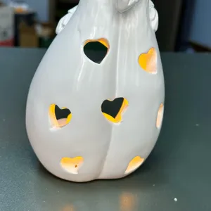 Detailed shot of white resin hugging candle holder with heart cutouts and warm LED glow.