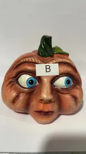 Funny pumpkin head Halloween decoration detail showing quirky big blue eyes resin face.