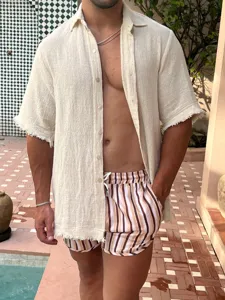 Detailed view of men's striped quick-dry beach shorts and casual textured shirt for summer holiday.