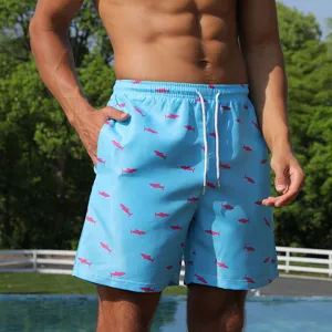 Close-up detail of light blue men's beach shorts featuring cute pink shark print and drawstring.