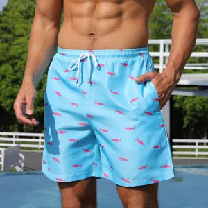 Close-up detail of light blue men's beach shorts featuring a playful pink shark pattern.