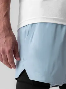 Vue rapprochée de short de sport homme avec tissu bleu clair respirant et doublure noire.