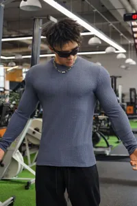 Detailansicht des strukturierten Langarm-Slim-Fit-Herrenpullovers im Fitnessstudio-Szenenstil.