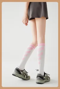 Nahaufnahme von Sportwadenstrümpfen mit rosa Streifen und Turnschuhen für das Training.