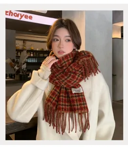 Detail view of the red plaid scarf with cozy tassels and warm texture worn by a model.