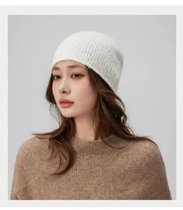 Gros plan du bonnet en maille cotees blanc montrant une texture laineuse douce et confortable.