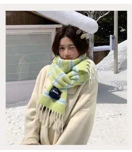 Closeup detail of Korean style winter striped scarf with fringe worn in snow scene background.