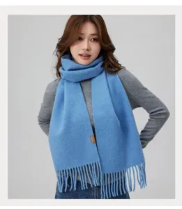 Gemütlicher blauer Winter-Strickschal für Damen mit Fransen und stilvollem Marken-Patch.