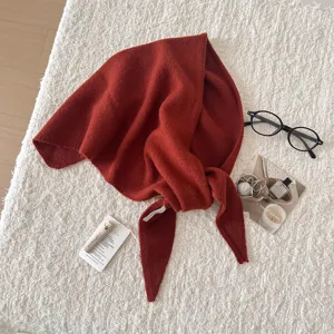 Dettaglio ravvicinato della comoda sciarpa triangolare in lana rossa con morbida trama.