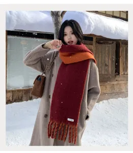 Cozy winter colorblock wool blend scarf detail with vibrant red and orange hues and fringe.