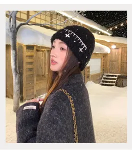 Winter black knit beanie hat with white cross embroidery details, warm and stylish chic accessory.
