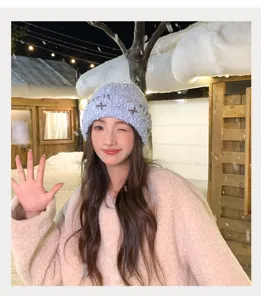 Winter warm knit beanie detail view, stylish light blue knitted hat with cute cross texture.