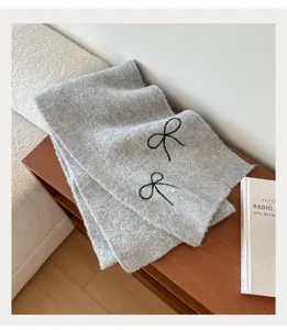 Grey knitted scarf with black bow embroidery, cozy winter fashion accessory for women.