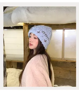 Detailed view of a cozy winter knit beanie featuring cute cross embroidery and soft fabric.
