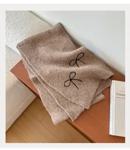 Cozy brown knitted winter scarf for women, featuring elegant black bow embroidery, warm daily wear.