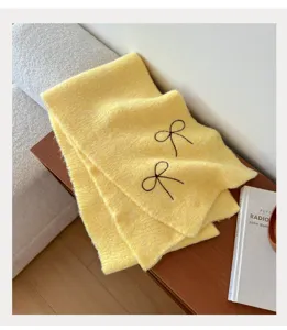 Yellow knitted scarf featuring black bow embroidery detail, cozy winter warmth accessory.