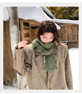 Detailansicht des kuscheligen Damen Winter Strickschals in Grün, stilvoll im Schnee getragen.