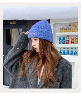 Detailed view of winter warm knitted beanie hat with pearl decoration, cozy wool material.