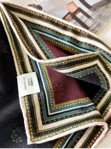 Détail de foulard en soie et laine raffiné, affichant une bordure géométrique élégante.