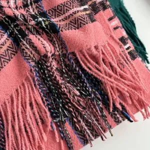 Close-up detail of winter plaid scarf showing fine weave texture and colorful fringe trim.