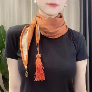 Close-up view of stylish two-tone neck scarf featuring elegant tassel and leaf pendant details.