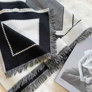Detailed view of a black and white geometric pattern tassel scarf, soft winter shawl.