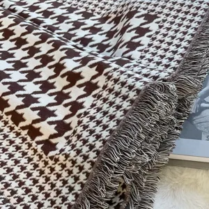 Vue détaillée d'une écharpe couverture à motif pied-de-poule marron et blanc avec franges.