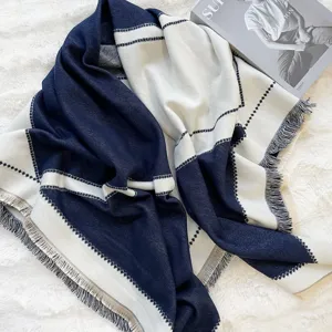 Detailed view of the cozy navy blue and off-white patterned cashmere-feel shawl with fringe.