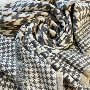 Gros plan détaillé d'une écharpe d'hiver classique à motif pied-de-poule avec franges douces.