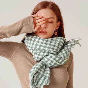 Close-up detail of green and white houndstooth pattern scarf with soft tassel fringe.